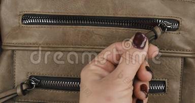 手用拉链把锁关上，一个棕色女包的口袋。 特写镜头。