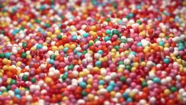 五颜六色的糖糖落在桌子上。 多种颜色的悬垂物落入五颜六色的球中。 红蓝绿色