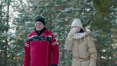 欢快的情侣在冬日的森林里笑着雪树上的风景。 快乐的男人和女人在雪地森林里玩得开心