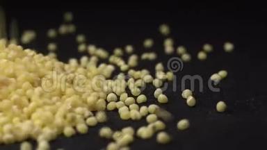 黄色小米倒在黑色背景的厨房黑色旋转桌上。 小米烹饪的美丽画面