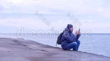 在阴天，人类正在海上海滨的智能手机上输入一条信息。