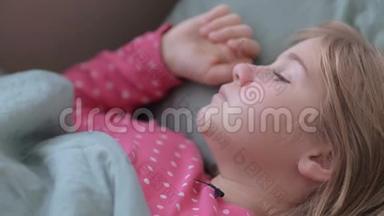 一个<strong>发烧</strong>的小女孩和一个女人的手抚摸她`肖像。 母亲照顾生病的孩子躺在床上