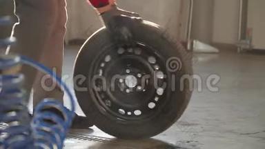 机械师在车库里拿着轮胎。 汽车修理厂的专业技工在客车上更换车轮