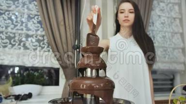 女孩在庆祝活动中搅动了一个巧克力喷泉。
