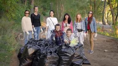 一队志愿者生态学家在<strong>清理</strong>森林领土后，在一堆<strong>垃圾</strong>袋附近摆姿势，一起微笑
