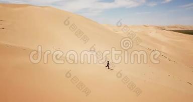 女孩在沙丘上奔跑。 鸟瞰蒙古戈壁沙漠的Khongor沙丘。