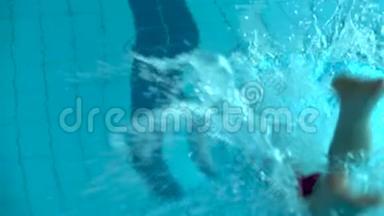 女孩游泳者在游泳池里潜水。 女游泳运动员潜入游泳池游泳。 上景。 关门