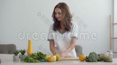 年轻有技能的女人站在现代厨房时把苹果放在桌子上。 健康食品的概念.. 职业