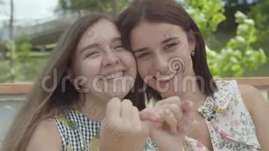 肖像两个可爱的女孩互相拿着对方`<strong>小手</strong>指和微笑，看着镜头。 简洁的手势
