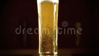 特写慢镜头冷光啤酒在一个高玻璃与水滴在酒吧背景。 快来点啤酒。 微波炉