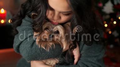 情绪激动的亚洲年轻女子在新年圣诞节的内部播放和抚摸一只毛茸茸的小狗。 新年概念