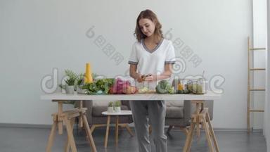 一个<strong>漂亮</strong>的女人在家中站在<strong>厨房</strong>的桌子旁，用刀子在<strong>厨房</strong>的切割板上切黄瓜