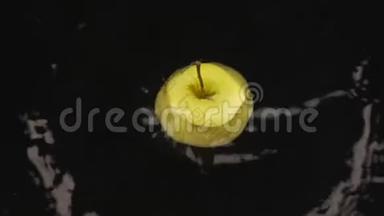 成熟、多汁的苹果切片落在一个覆盖着水的黑色表面上。 慢动作。