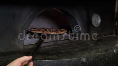 意大利比萨饼是在烤箱里煮的，餐厅厨师在餐厅用木头烤的烤箱里拿出比萨饼。