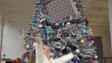 小可爱的女孩把礼物盒和圣诞树放在一起