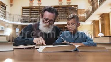 一位12岁的金发孙子和他那位年长的聪明的爷爷一起在图书馆看书的正面景色