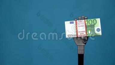 一只机械手握着一捆欧元。 一只灰色的半机人手在蓝色背景上拿着钱。
