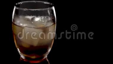 特写镜头。 冰块在一杯威士忌中旋转融化。 孤立在白色背景上。 在威士忌中旋转冰块
