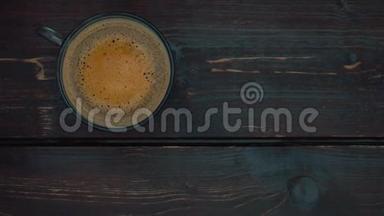 咖啡泡沫在玻璃杯中与咖啡一起旋转。 桌子的深褐色表面。 从上往下看。 慢动作