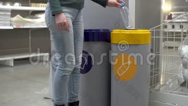 一个年轻的女人把一个塑料瓶扔进垃圾桶。 垃圾分类专用容器.. 塑料容器。
