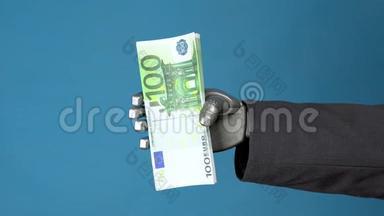 穿西装的cyborg商人持有一包欧元。 一只机械手在蓝色背景上显示了一捆钱。