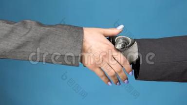 一个年轻的女人摇动着一个半机械人的灰色手臂。 两个商人的握手。 <strong>双手特写</strong>在蓝色