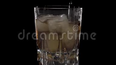冰块在一杯威士忌中旋转融化。 孤立在白色背景上。 在白色威士忌中旋转冰块