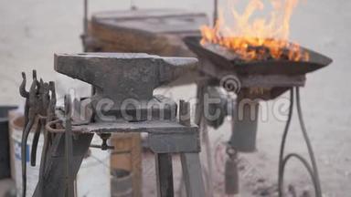 一个街道的锻炉，一个火在炉中燃烧，一个铁砧与一个工具放置。