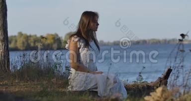 神秘的高加索女人坐在湖岸上环顾四<strong>周</strong>。 穿着<strong>浅色</strong>白裙休息的漂亮女孩