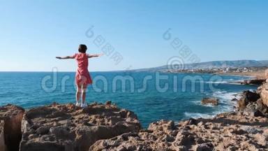 迷人的女孩站在悬崖边，伸出手臂向两边。 穿<strong>红裙子</strong>的白种人女孩站在虚张声势