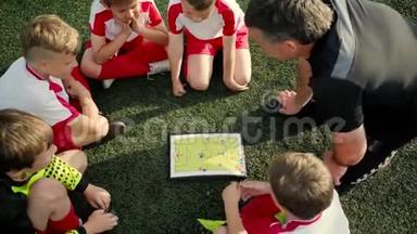 <strong>男孩子</strong>们的足球运动员都在听教练的训练，并且正在考虑比赛计划