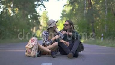年轻的白种人夫妇坐在路上的森林背景。 <strong>戴草帽</strong>的女人，<strong>戴草帽</strong>的男人