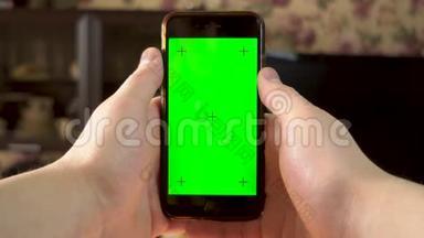 那个人用电话。 手使手指点击智能手机与绿色屏幕。 铬钥匙。