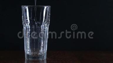 黑色背景上的玻璃。 把水倒进杯子里。 透明容器。 纯净水。
