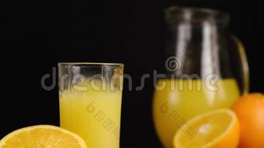 冰块落在一杯橙汁或柠檬水中，上面有橘子和水罐。