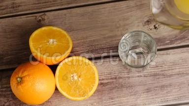 从水罐倒出的新鲜黄色果汁的顶部视图是在木桌上用橘子倒入一个高玻璃杯中。