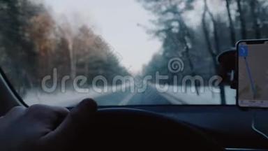 特写司机`手握汽车方向盘在冬季<strong>道路</strong>上驾驶，智能手机<strong>导航</strong>应用程序慢动作。