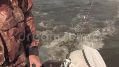 渔夫用马达控制一艘<strong>充气船</strong>，在湖边钓鱼。