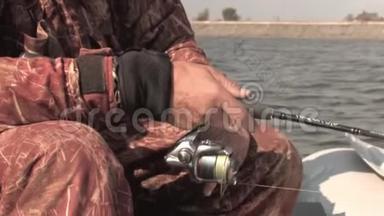 一个钓鱼的人，坐在橡皮船上，用一根纺棒钓鱼，把鱼卷拧成一团，把鱼线卷起来。