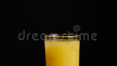 冰块落在一杯橙汁或柠檬水的黑色背景上。