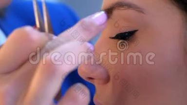 化妆师将人造睫毛涂抹在沙龙、<strong>眼部</strong>特写的女孩模特身上。