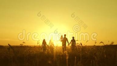 幸福童年的概念.. 幸福的大家庭在夕阳下穿过田野。 父母和三个孩子走进来