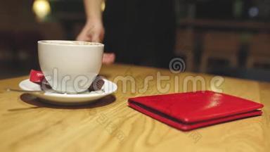 服务员手拿<strong>走红</strong>色皮革或检查文件夹和空咖啡杯