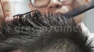 一个非常亲密的男人`手与理发师在眼镜剪发用剪刀。
