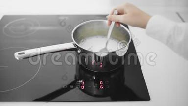牛奶在平底锅里沸腾. 女人用平底锅搅拌牛奶