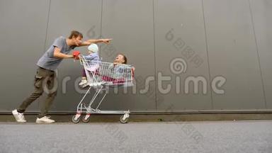 购物背景。 快乐的父亲和孩子在购物车里，手推车推着手推车前进。 购物