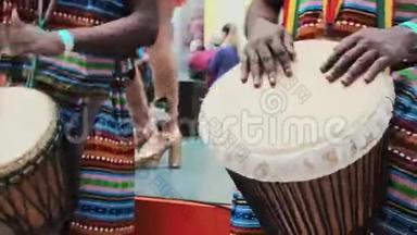 特写非洲的手在djembe鼓上演奏特写。 音乐家在非洲鼓上敲打节奏。 黑人艺术家们