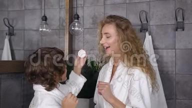 可爱的妈妈和她的儿子在浴室里享受护肤霜的迷人肖像