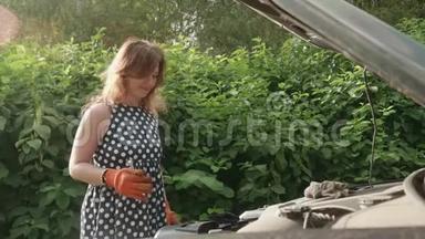 穿斑点衣服的女孩把小扳手放进工具箱里。 她在经理修理汽车后高兴地笑了。