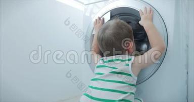 可爱的小男孩看着洗衣机里。 气缸旋压机.. 工业概念洗衣机